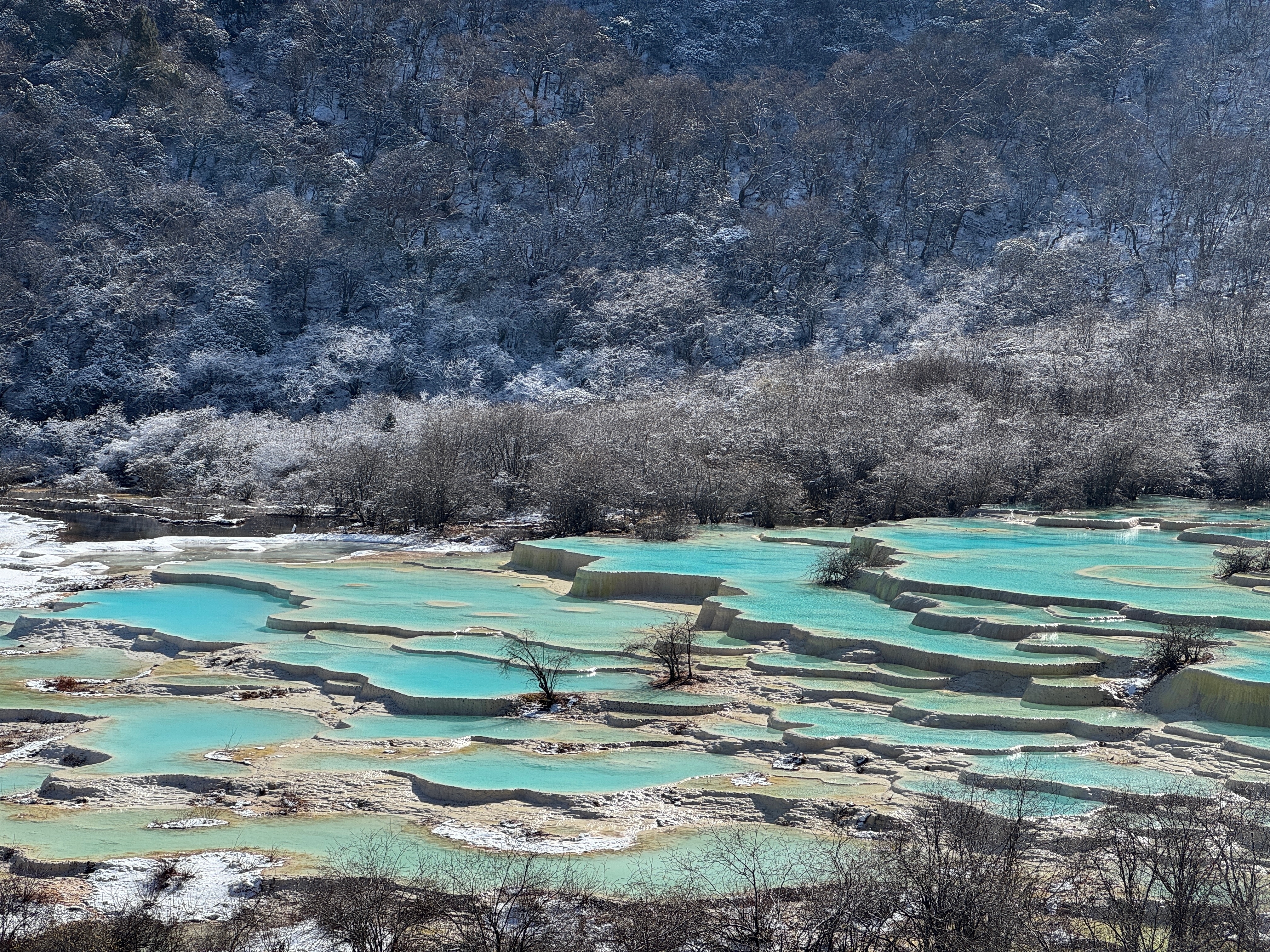 หิมะขาวโพลนตัดกับน้ำสีฟ้าใน Huanglong National Park